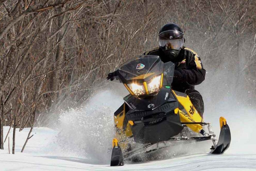 yellow snowmobile kicking up snow